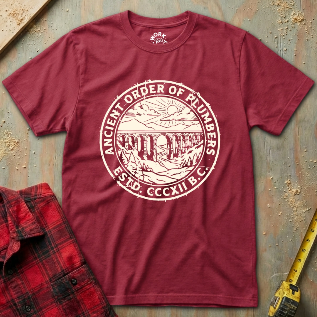 Maroon t-shirt with 'Ancient Order of Plumbers' logo on a textured surface.