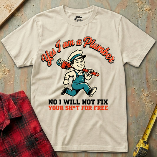 Beige t-shirt with plumber graphic and text on a textured surface with tools.