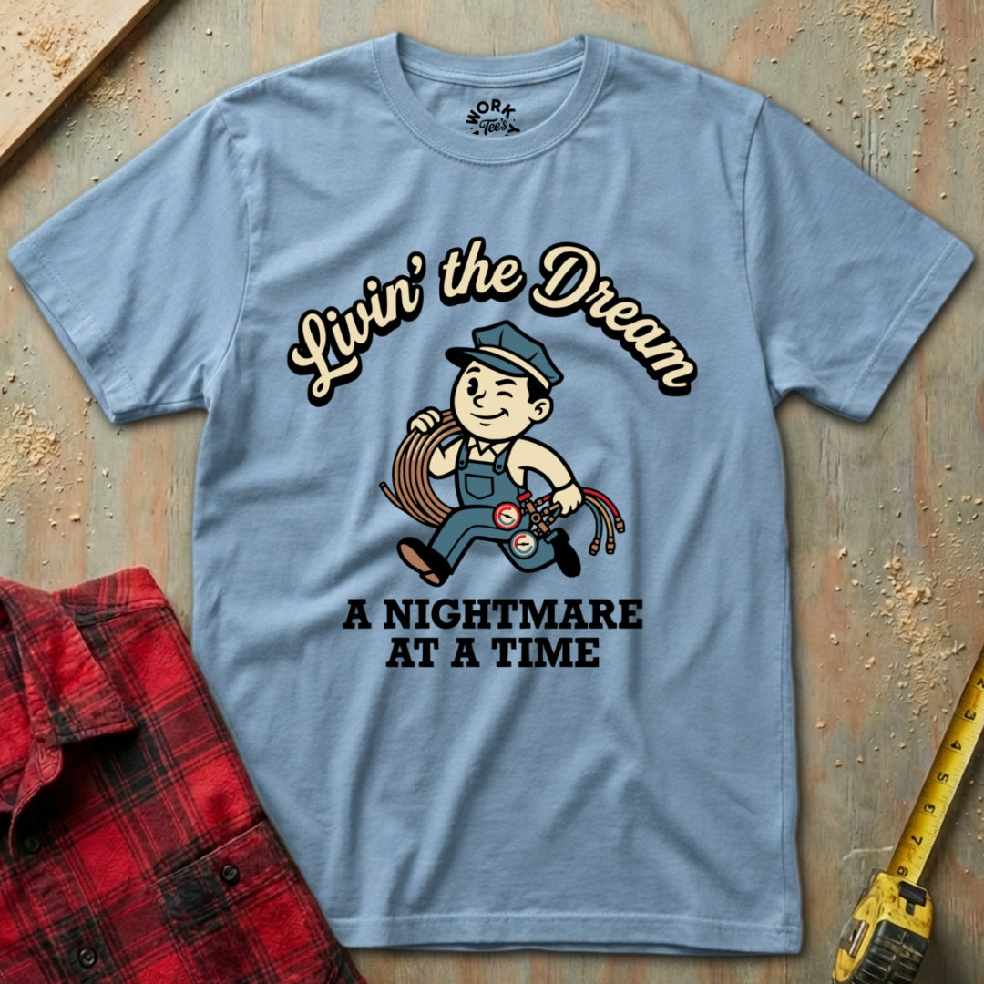 Blue t-shirt with graphic design and text on a wooden surface with plaid shirt and tape measure.