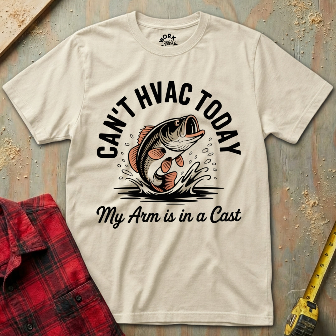 Beige t-shirt with fishing graphic and text on a textured surface with plaid shirt and tape measure.