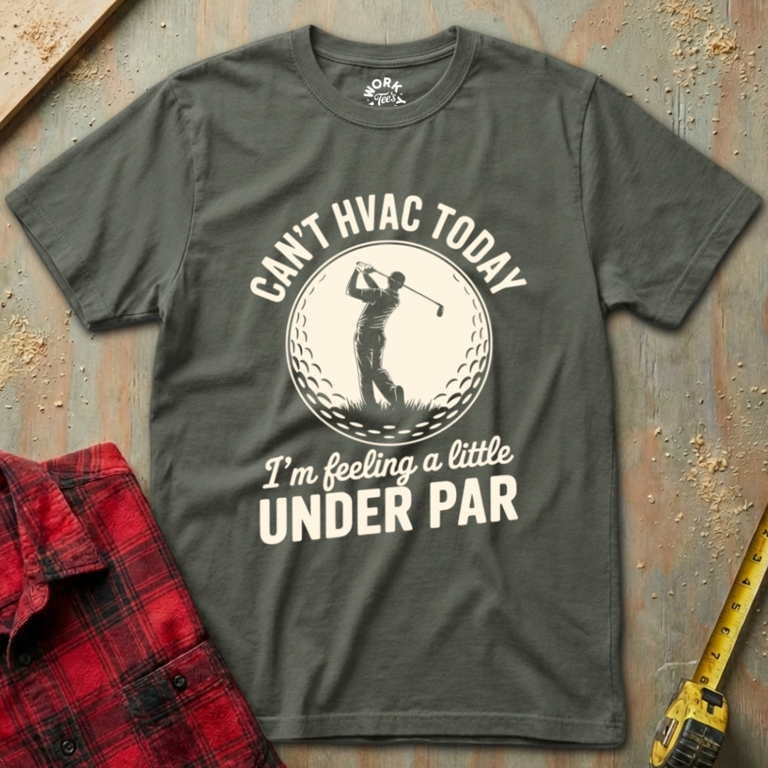 Gray t-shirt with golf-themed text on a textured surface with a red plaid shirt and yellow tool.