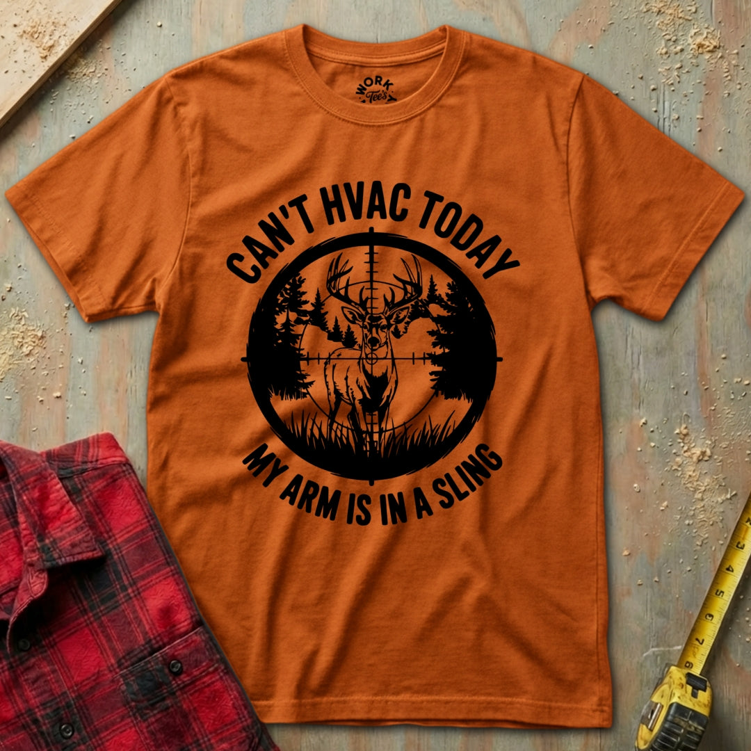 Orange t-shirt with black graphic and text on a textured surface with a red plaid shirt and yellow tool in the background.