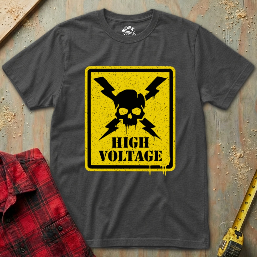 Gray t-shirt with high voltage graphic on a textured surface with red plaid shirt and yellow tool.