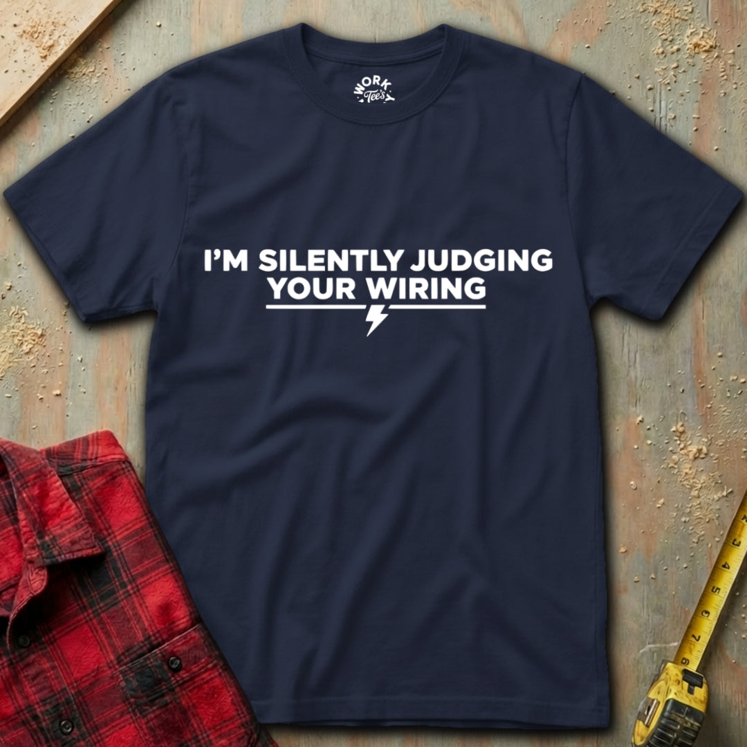Navy blue t-shirt with humorous text design on a textured surface with tools.