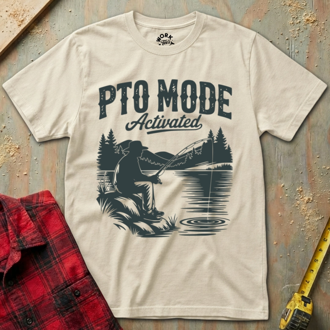 Beige t-shirt with fishing graphic and 'PTO Mode Activated' text on a textured surface.