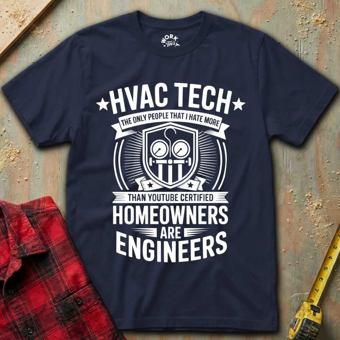 Navy blue t-shirt with white text and graphics on a textured surface with a red shirt and yellow tool in the background.