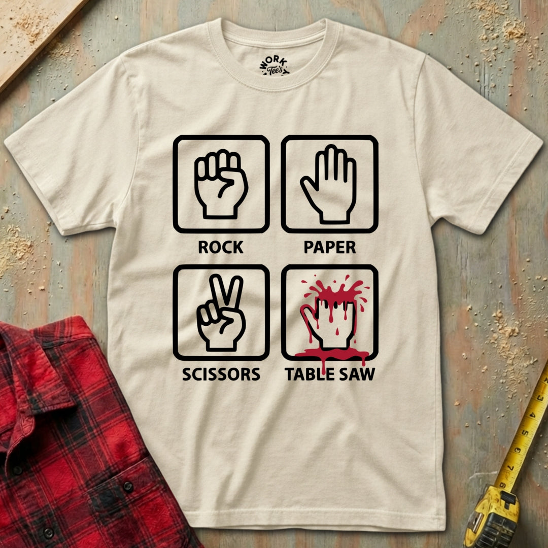 Beige t-shirt with 'Rock Paper Scissors Table Saw' graphic design on a textured surface.