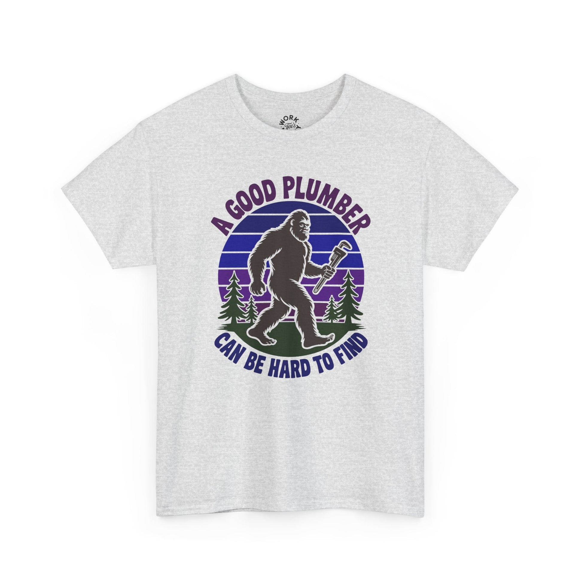 White t-shirt with a graphic of a bigfoot-like creature holding a wrench, surrounded by trees, with text 'A good plumber can be hard to find' on a white background.
