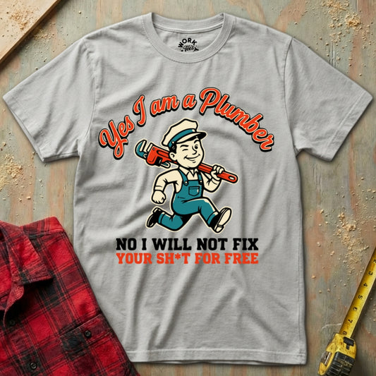 Gray t-shirt with a plumber graphic and text on a wooden surface with tools.