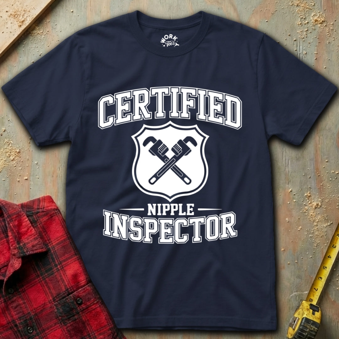 Navy blue t-shirt with 'Certified Nipple Inspector' text and graphic on a textured surface.