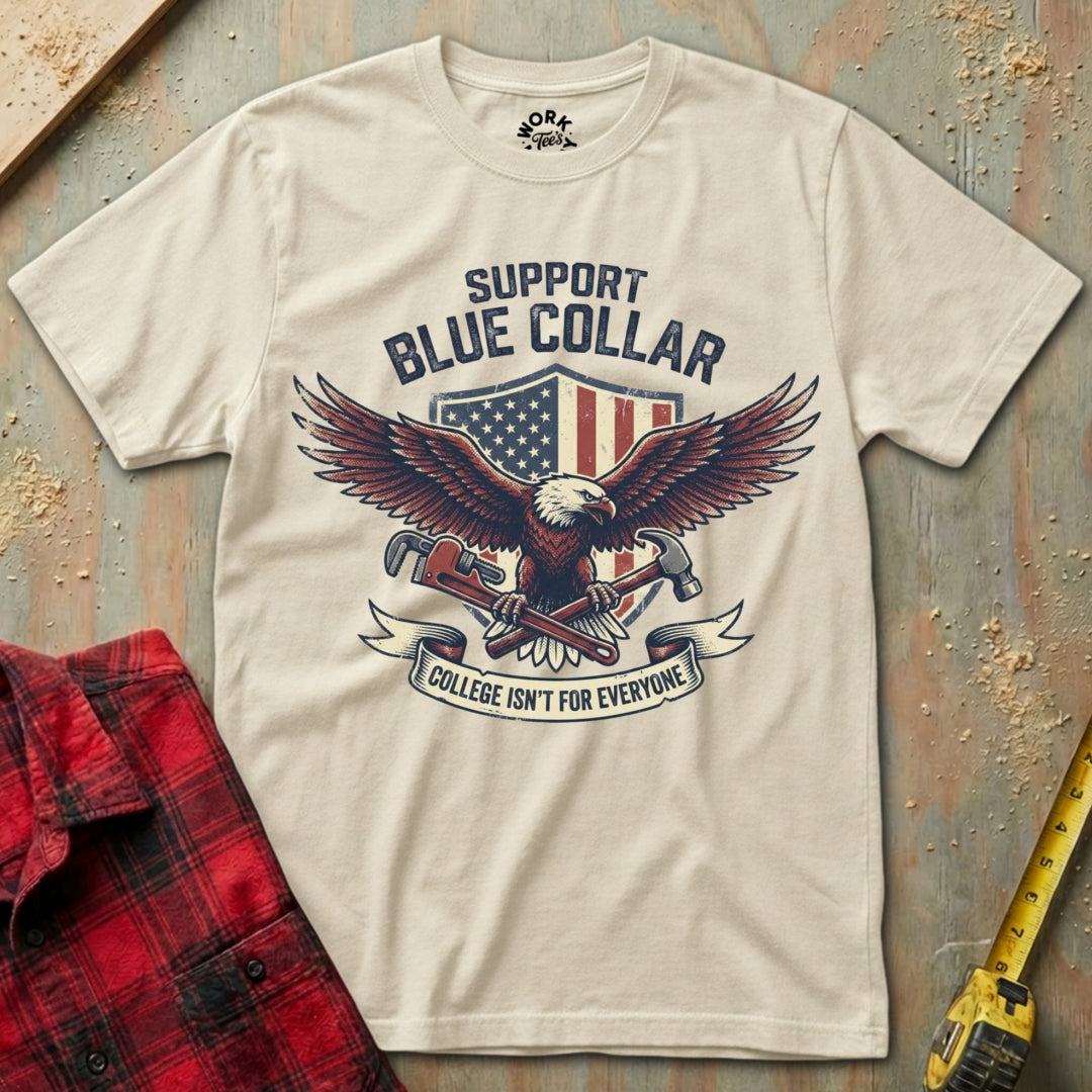 Beige t-shirt with eagle graphic and text on a textured surface with plaid shirt and tape measure.