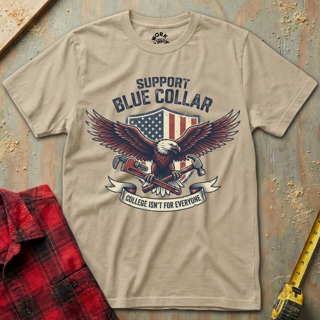 Beige t-shirt with eagle graphic and text on a wooden surface with plaid shirt and tape measure.