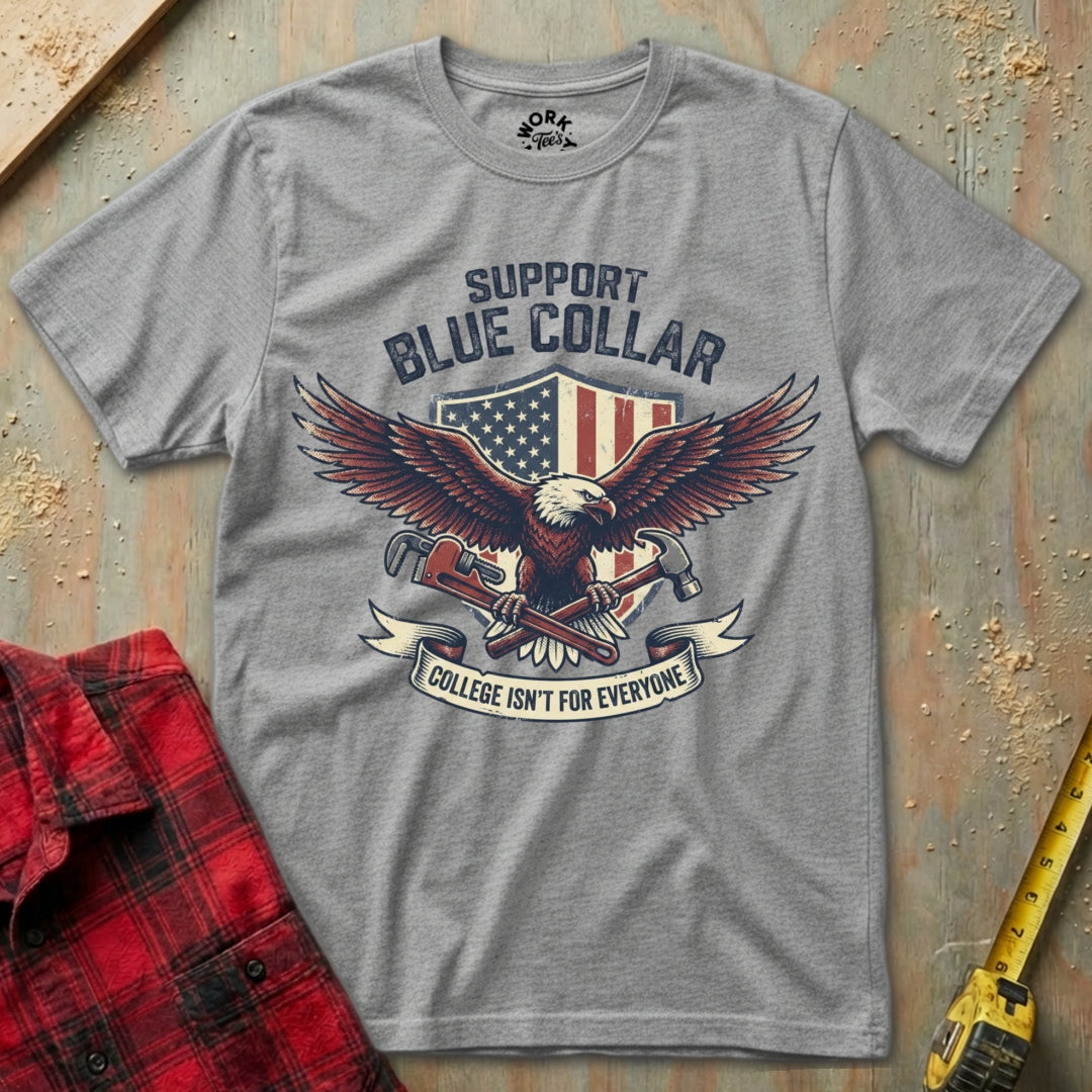 Gray t-shirt with eagle graphic and text on a textured surface with plaid shirt and tape measure.