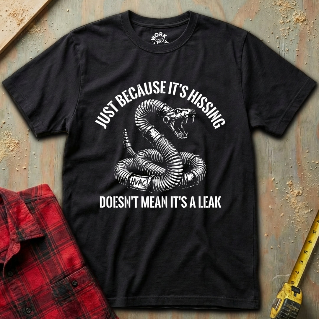 Black t-shirt with snake graphic and text on a textured surface with red plaid shirt and yellow tool in background