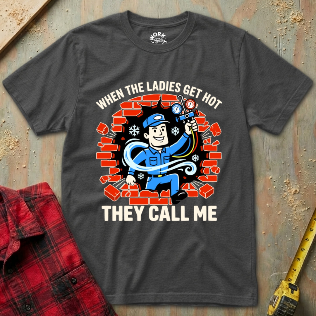 Gray t-shirt with a graphic design and text on a textured surface with a red plaid shirt and yellow tool in the background.