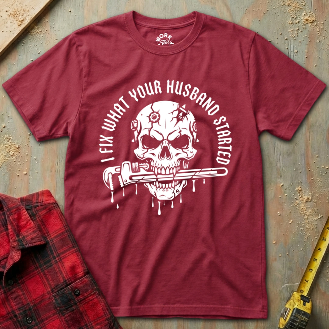 Red t-shirt with skull graphic and text on a textured surface with plaid shirt and tape measure.