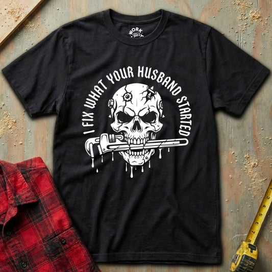 Black t-shirt with skull graphic and text on a textured surface with plaid shirt and tape measure.