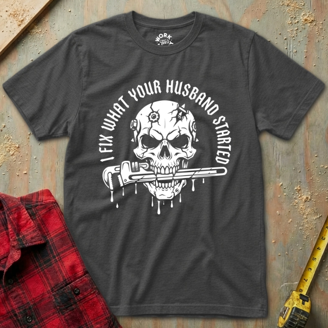 Dark Heather t-shirt with skull graphic and text on a textured surface with plaid shirt and tape measure.