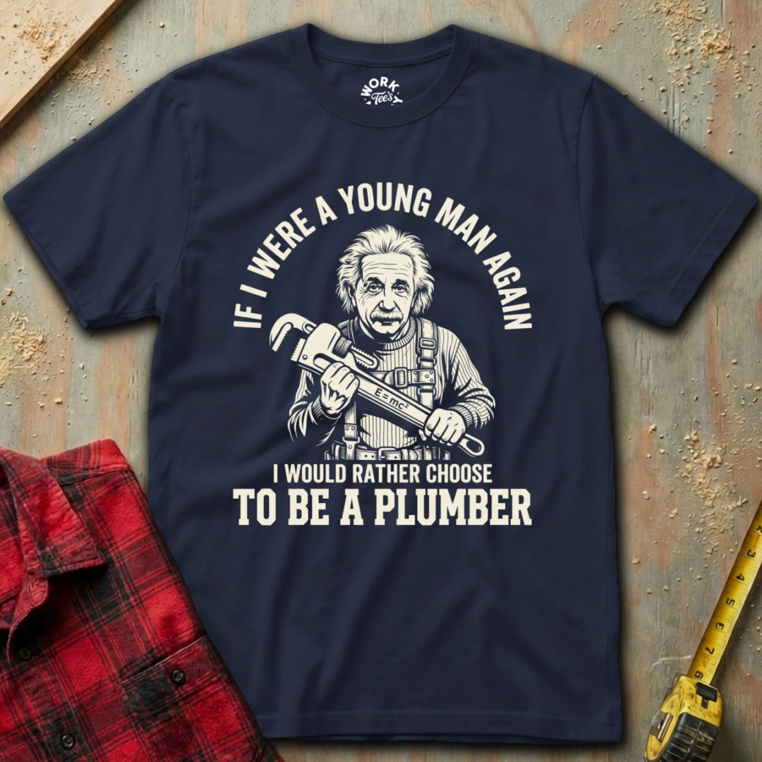 Navy blue t-shirt with a graphic and text about choosing to be a plumber, placed on a textured surface with tools.