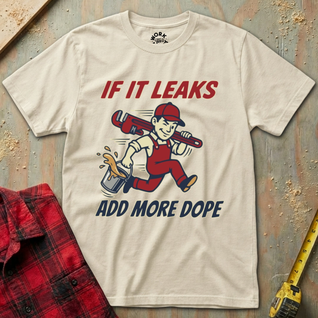 Beige t-shirt with graphic design and text on a textured surface with plaid shirt and tape measure.