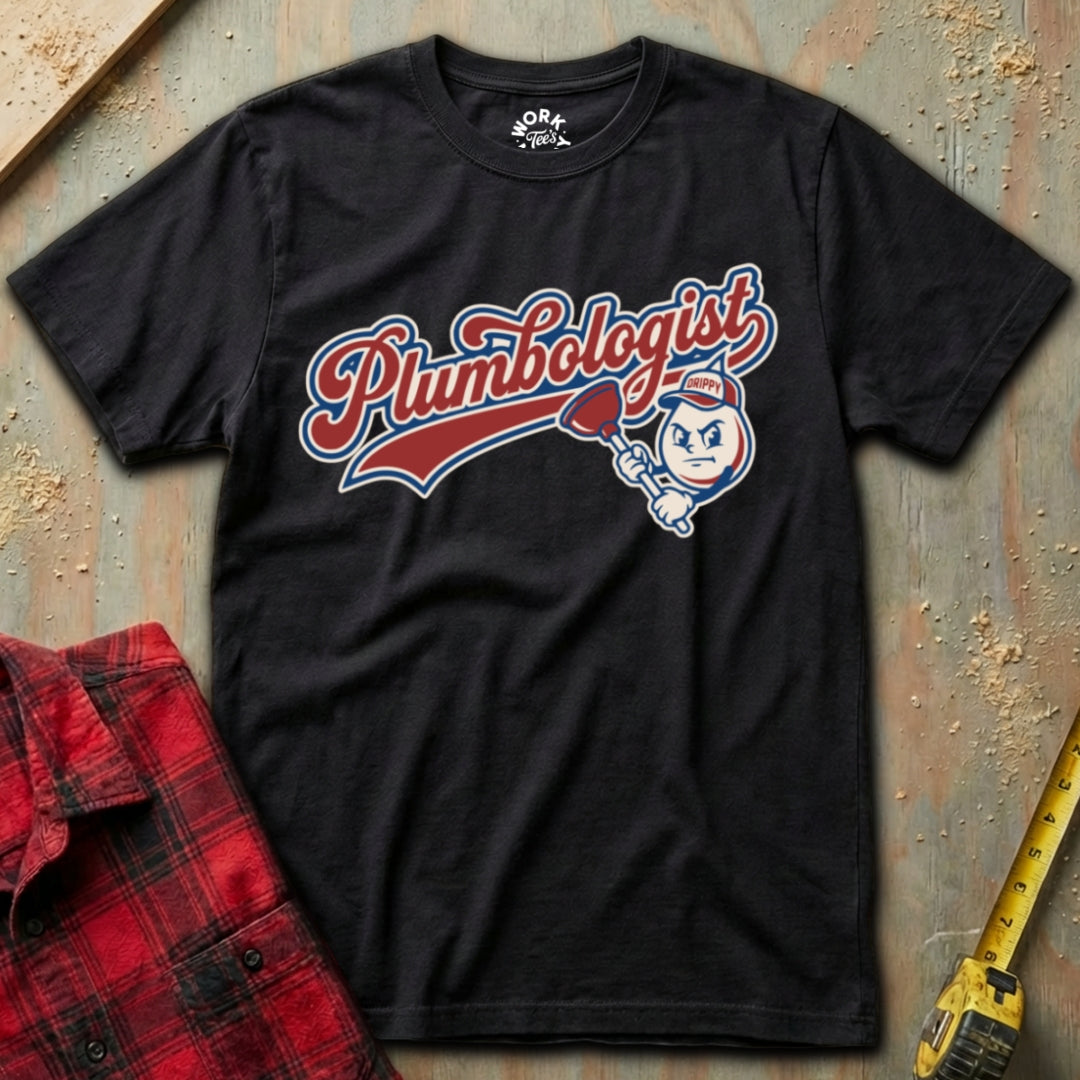 Black t-shirt with 'Plumbologist' graphic on a textured surface with a red plaid shirt and yellow tool in the background.