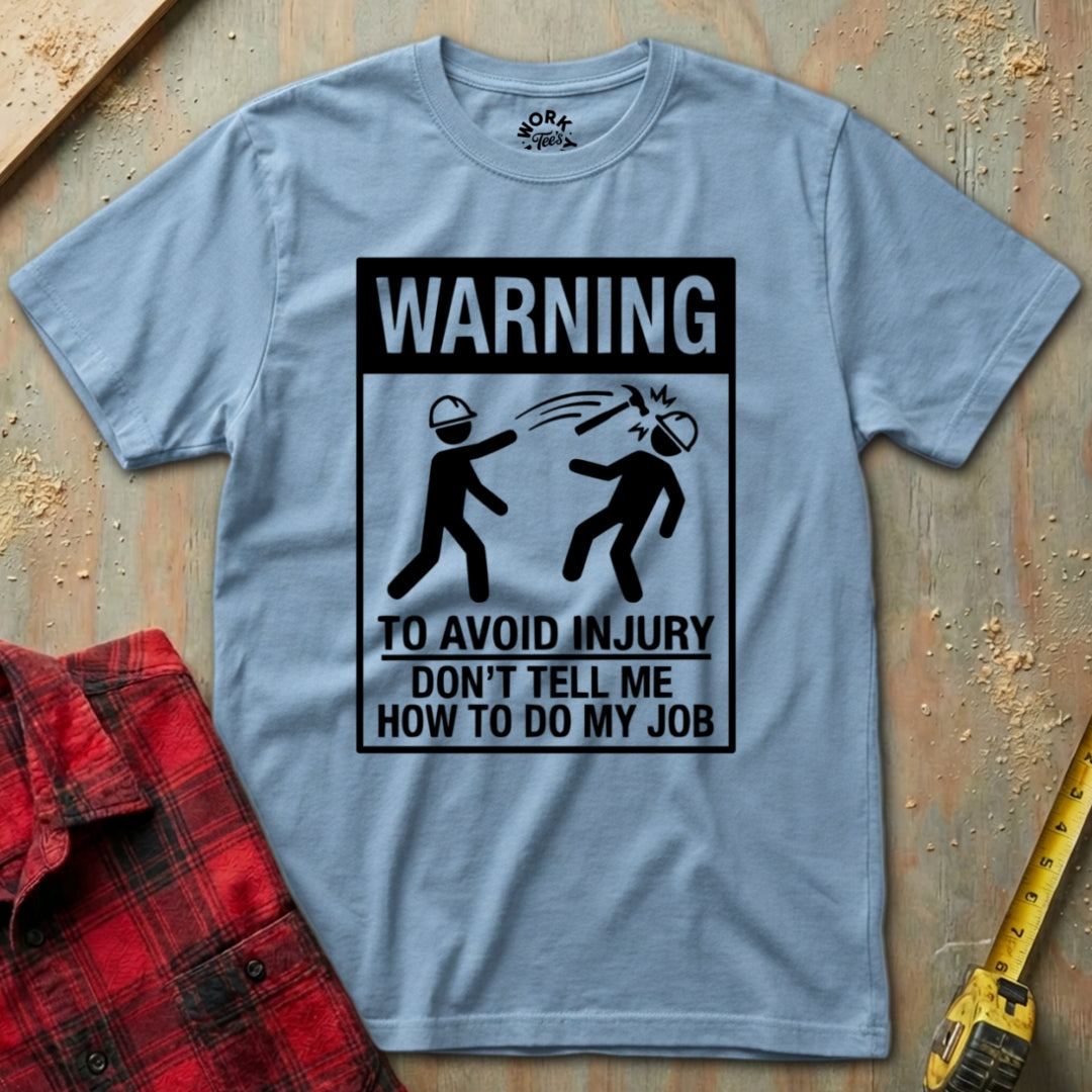 Gray t-shirt with a humorous warning graphic on a wooden surface with tools.