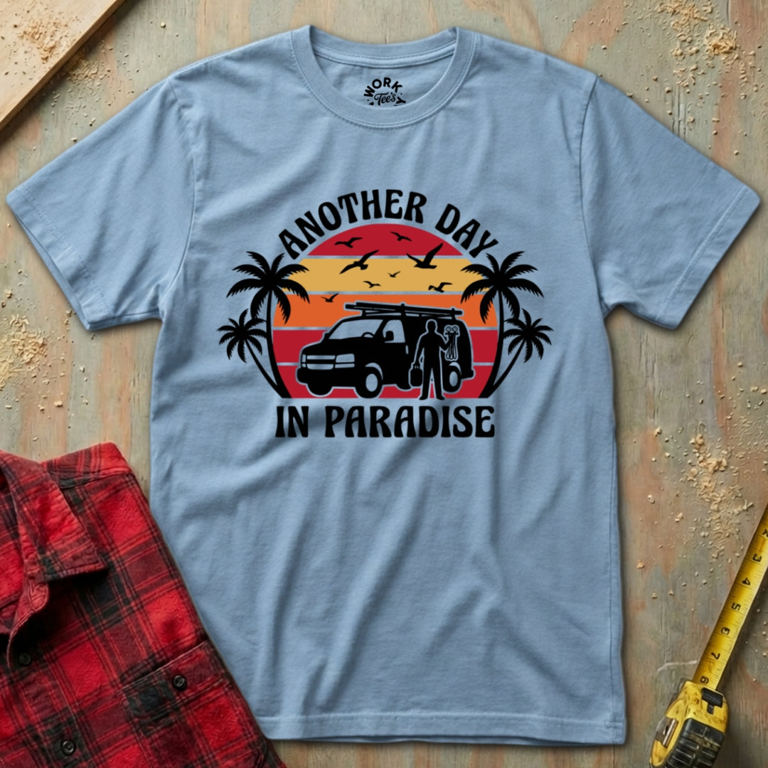 Gray t-shirt with 'Another Day in Paradise' graphic on a wooden surface with a red shirt and tape measure.