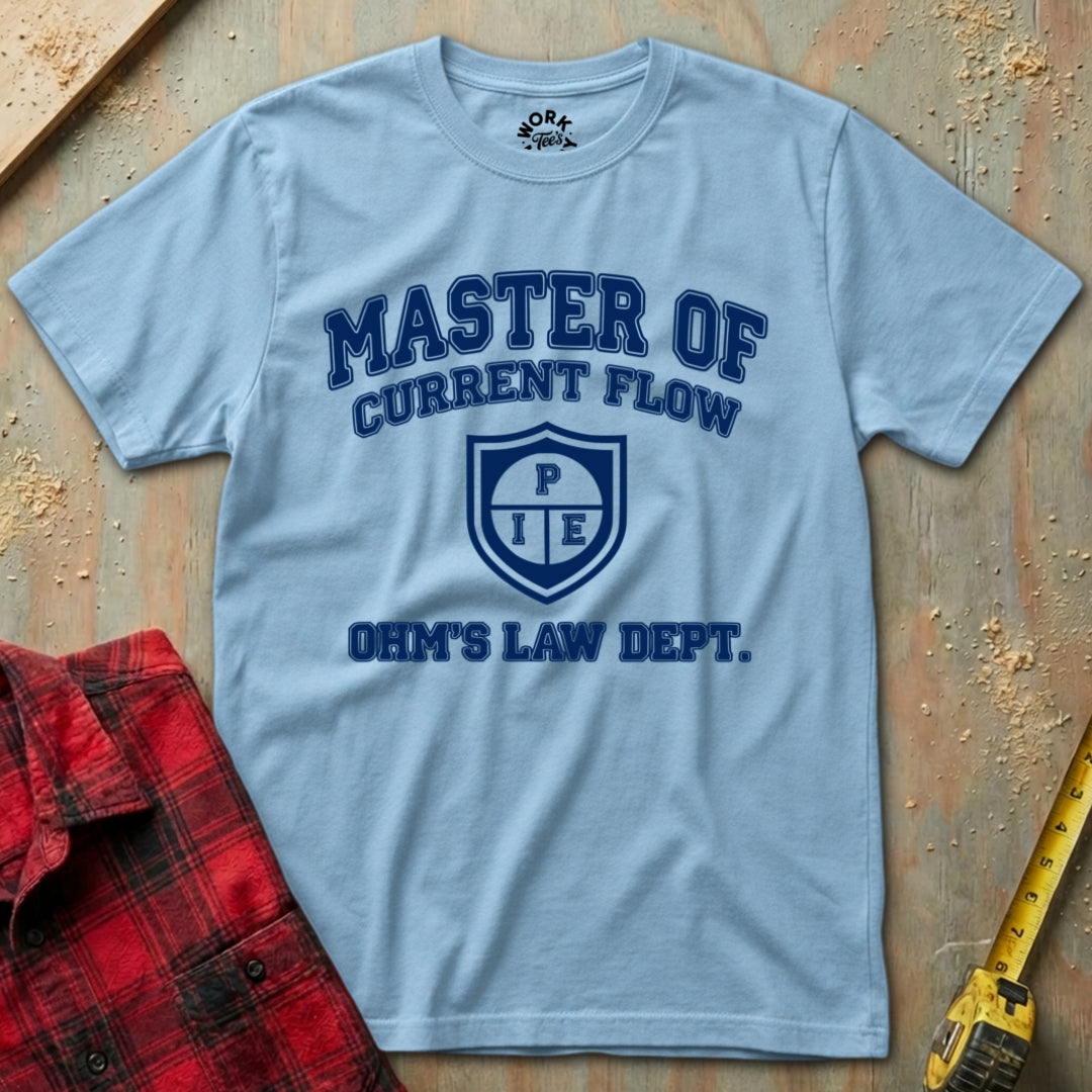Light blue t-shirt with 'Master of Current Flow' text on a wooden surface with a red plaid shirt and yellow tool.