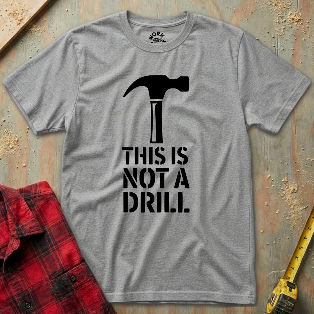 Gray t-shirt with a hammer graphic and text 'THIS IS NOT A DRILL' on a textured surface.