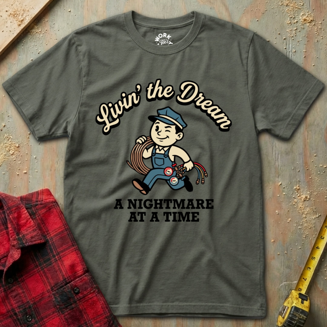 Gray t-shirt with graphic design and text on a textured surface with plaid shirt and tape measure.