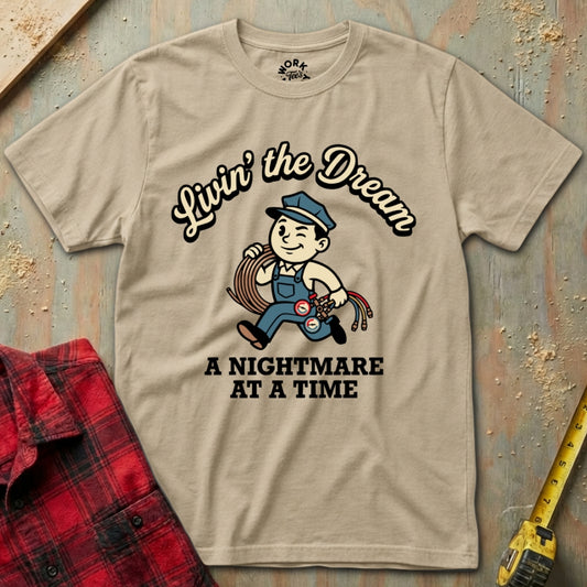 Beige t-shirt with graphic design and text on a wooden surface with plaid shirt and tape measure.