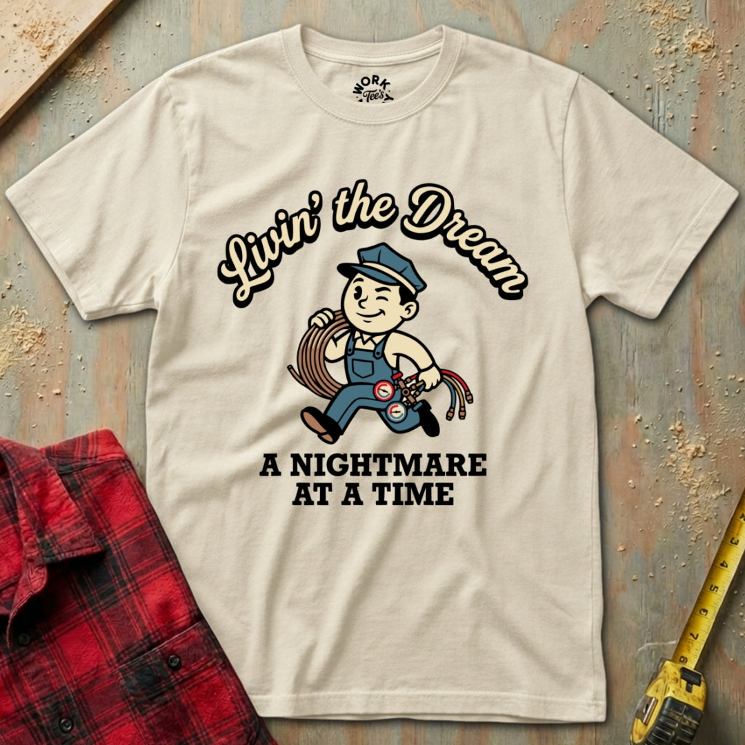 Beige t-shirt with graphic design and text on a textured surface with plaid shirt and tape measure.