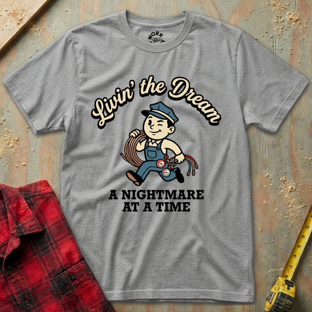 Gray t-shirt with graphic design and text on a wooden surface with plaid shirt and tape measure.