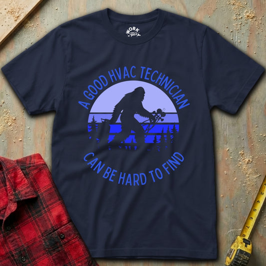 Navy blue t-shirt with HVAC technician graphic and text on a textured surface with tools.