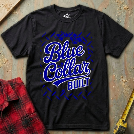 Black t-shirt with 'Blue Collar Built' text on a textured surface with a red plaid shirt and yellow tool in the background.