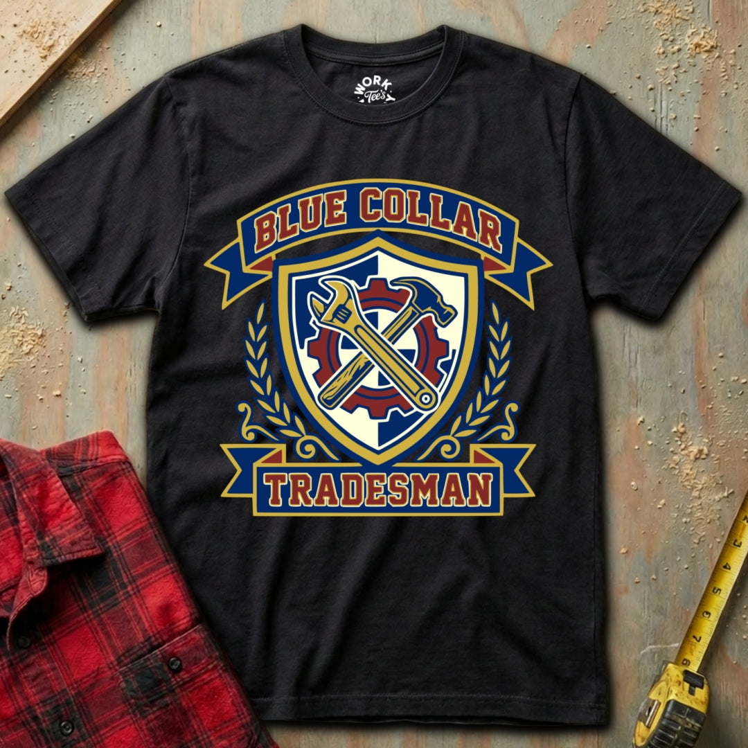 Black t-shirt with 'Blue Collar Tradesman' graphic design on a textured surface with plaid shirt and tape measure.