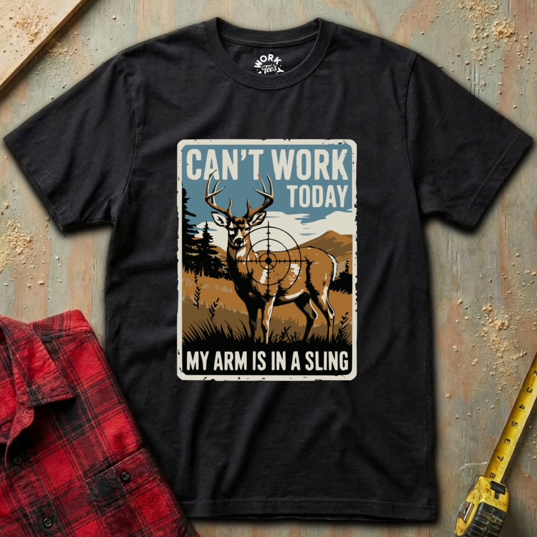 Black t-shirt with a graphic of a deer and text 'Can't Work Today, My Arm is in a Sling' on a textured surface.