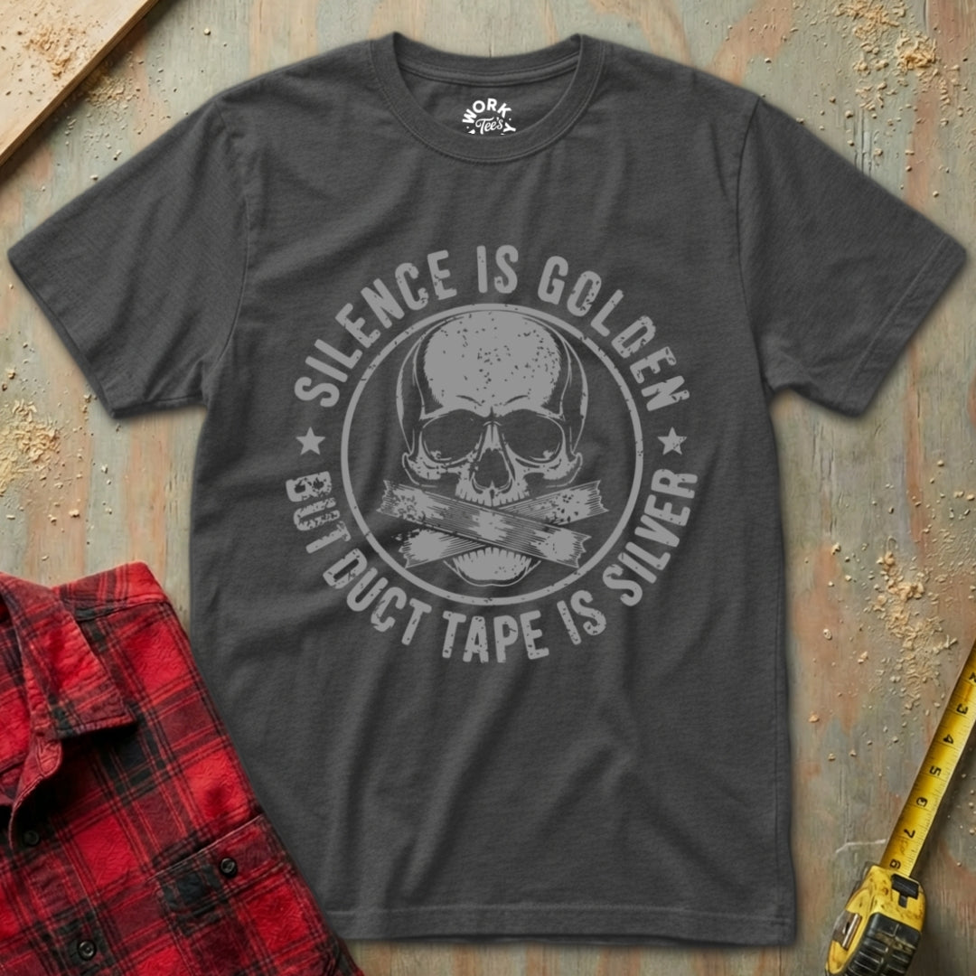 Gray t-shirt with skull design and text on a textured surface with red plaid shirt and yellow tape measure.