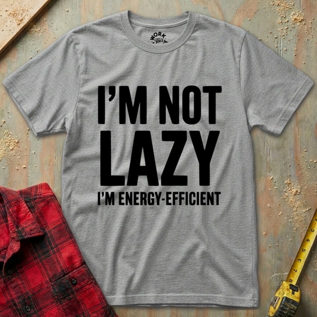 Gray t-shirt with 'I'm not lazy, I'm energy-efficient' text on a textured surface with a red plaid shirt and yellow tool in the background.