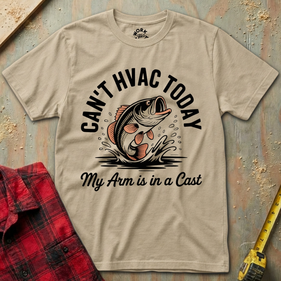 Beige t-shirt with a fish graphic and text on a wooden surface with a red plaid shirt and yellow tool.