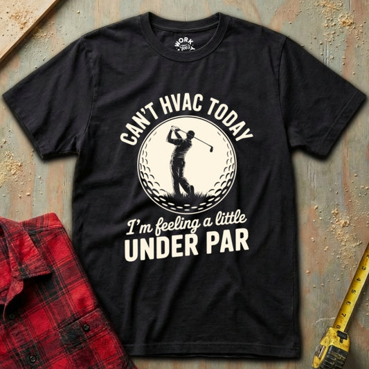 Black t-shirt with golf-themed text and graphic on a textured surface with a red shirt and yellow tool in the background.
