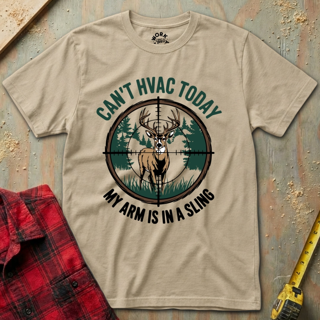 Beige t-shirt with hunting graphic and text on a wooden surface with plaid shirt and tape measure.
