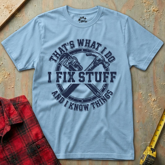 Light blue t-shirt with graphic design and text on a wooden surface with tools.
