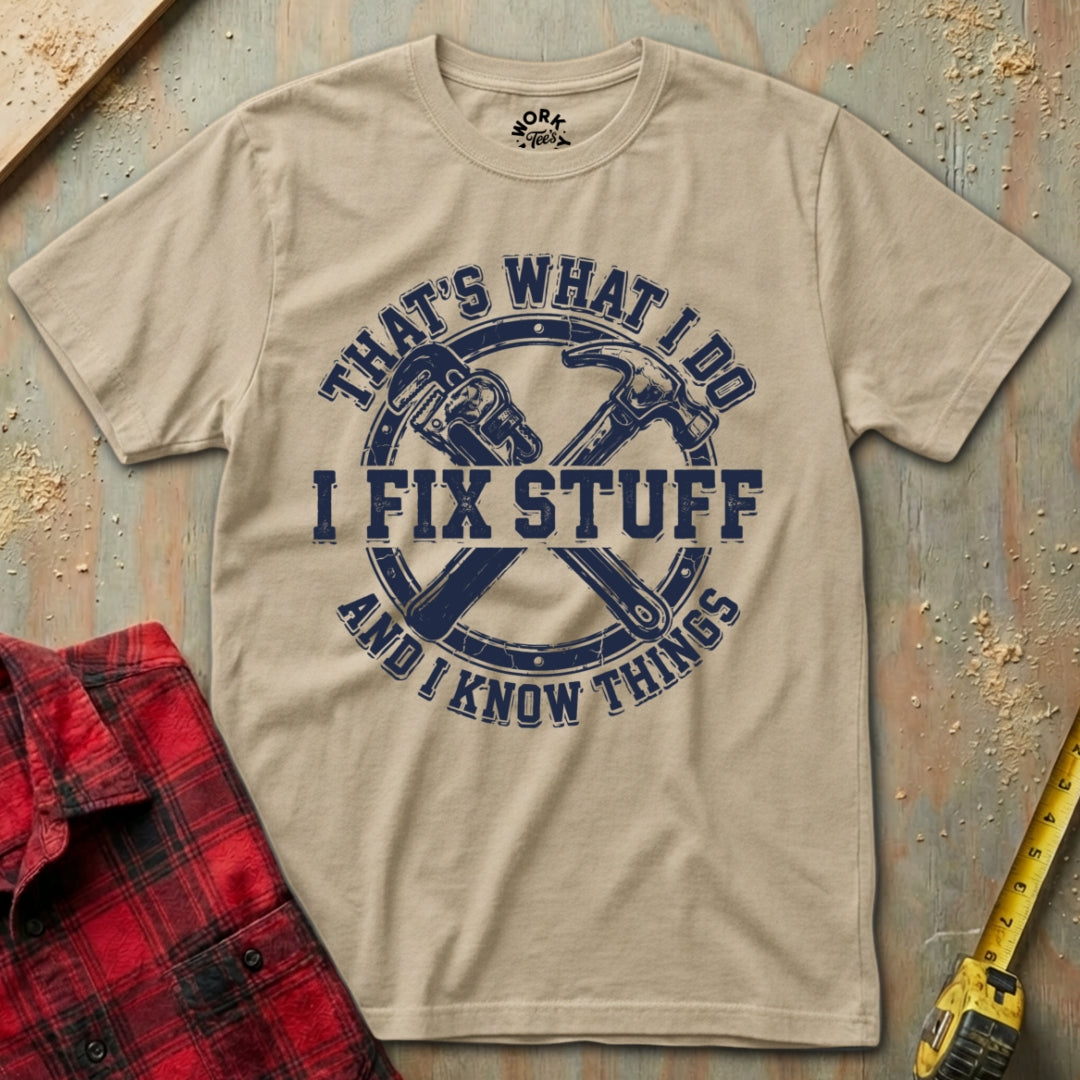 Beige t-shirt with blue graphic and text 'I Fix Stuff and I Know Things' on a wooden background.