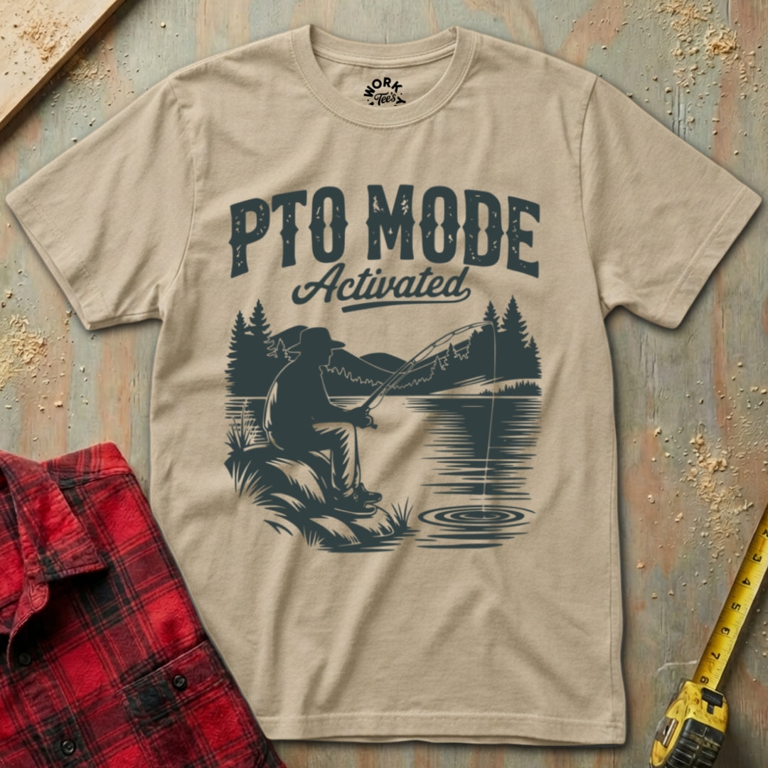 Beige t-shirt with bear fishing graphic and 'PTO Mode Activated' text on a wooden surface.