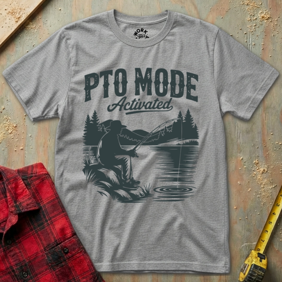 Gray t-shirt with 'PTO Mode Activated' graphic on a textured surface with plaid shirt and tape measure.