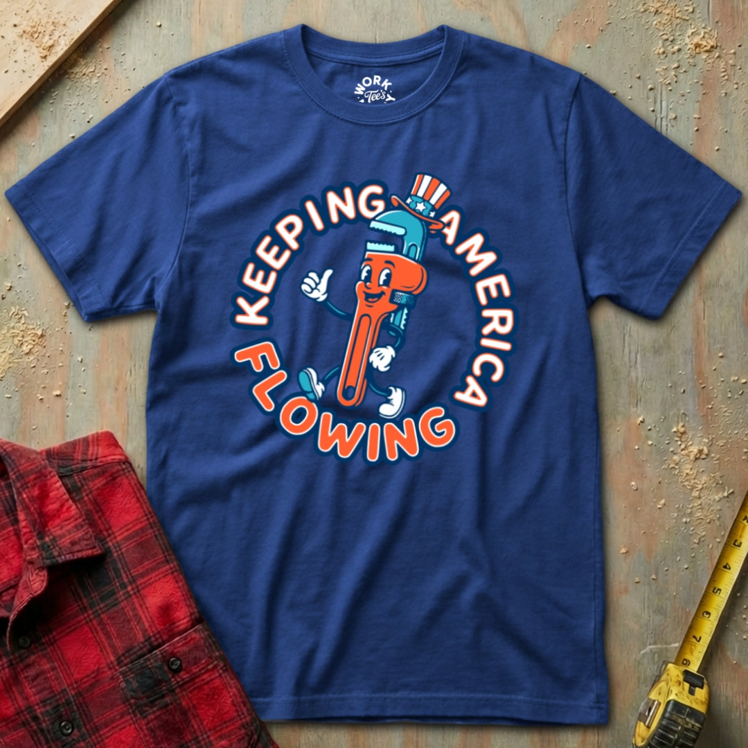 Blue t-shirt with a cartoon character and text 'Keeping America Flowing' on a textured surface.