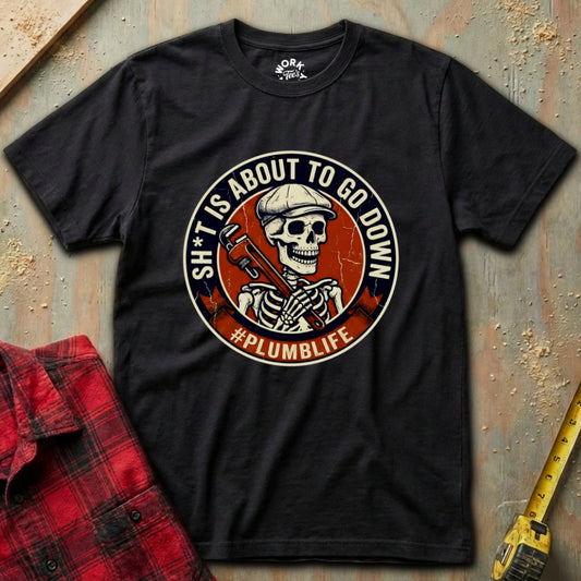 Black t-shirt with a skeleton graphic and text on a textured surface with a red flannel shirt and yellow tool in the background.