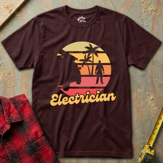 Maroon t-shirt with 'Electrician' graphic design on a textured surface with tools.