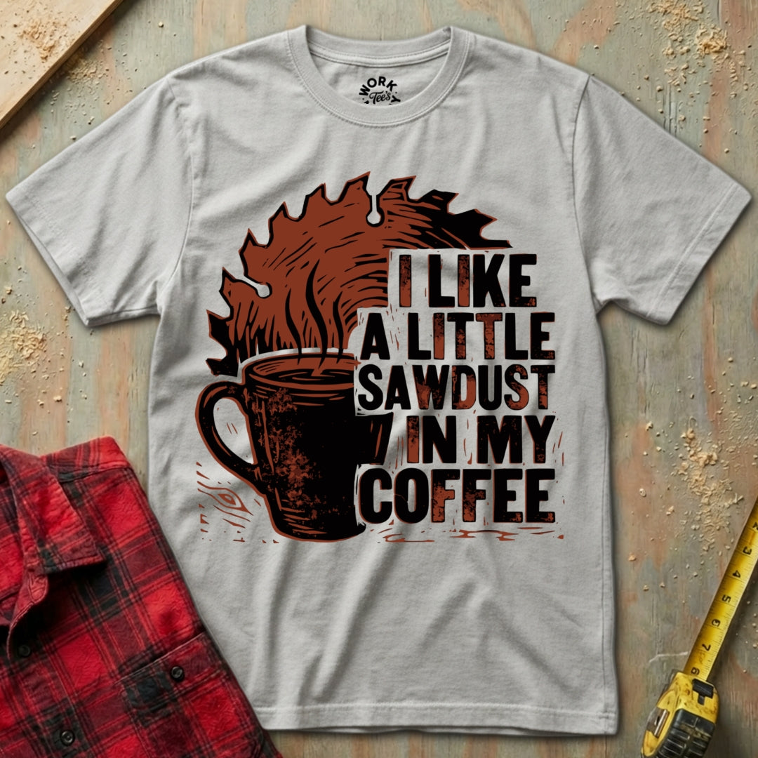 Gray t-shirt with coffee graphic and text on a wooden surface with plaid shirt and tape measure.